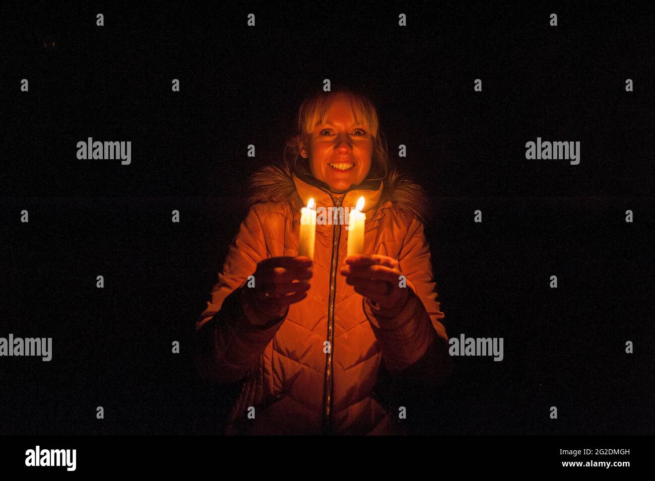 A woman holds two candles in the darkness Stock Photo