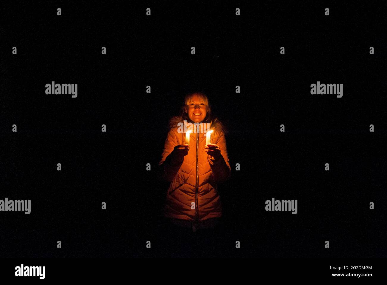A woman holds two candles in the darkness Stock Photo