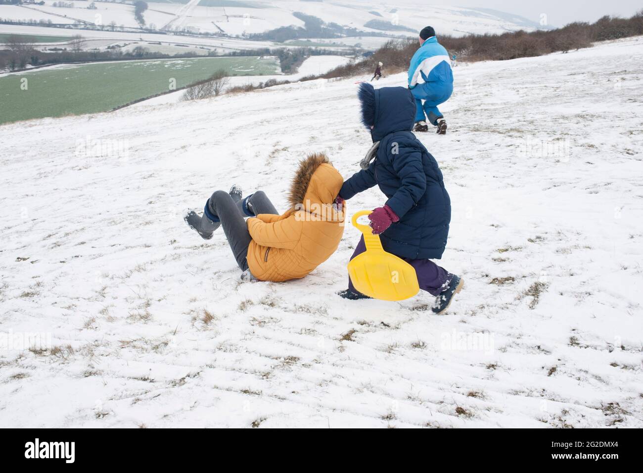 A family has fun sledging on Mill Hill in Shoreham-by-Sea, West Sussex after a light covering of snow on the ground. Stock Photo