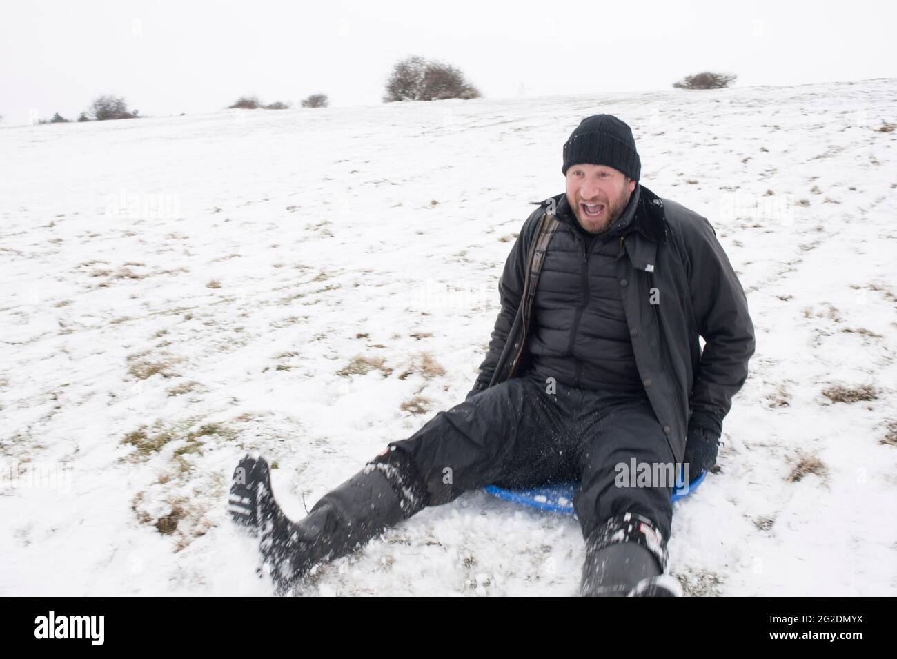 A family has fun sledging on Mill Hill in Shoreham-by-Sea, West Sussex after a light covering of snow on the ground. Stock Photo