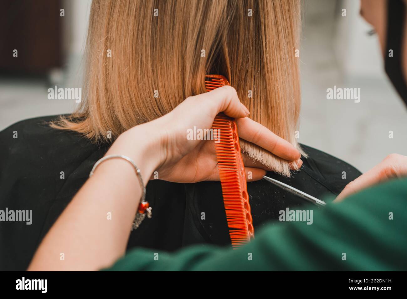 Female hairdresser holds in hand between fingers blond hair, comb and
