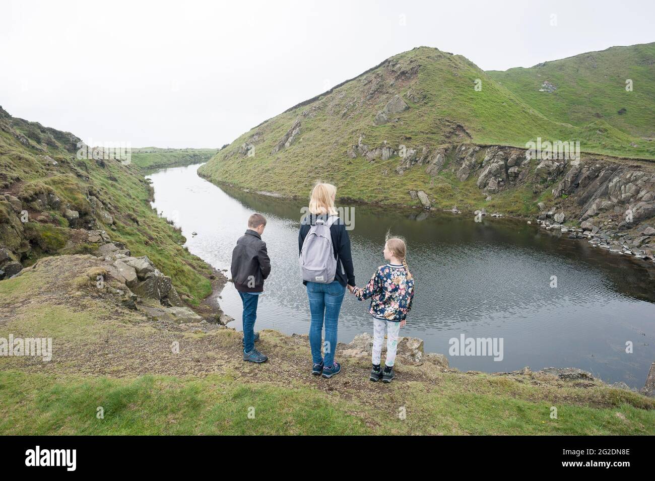 A mother stands with her kids looking at a body of water and hills in Shropshire England Stock Photo