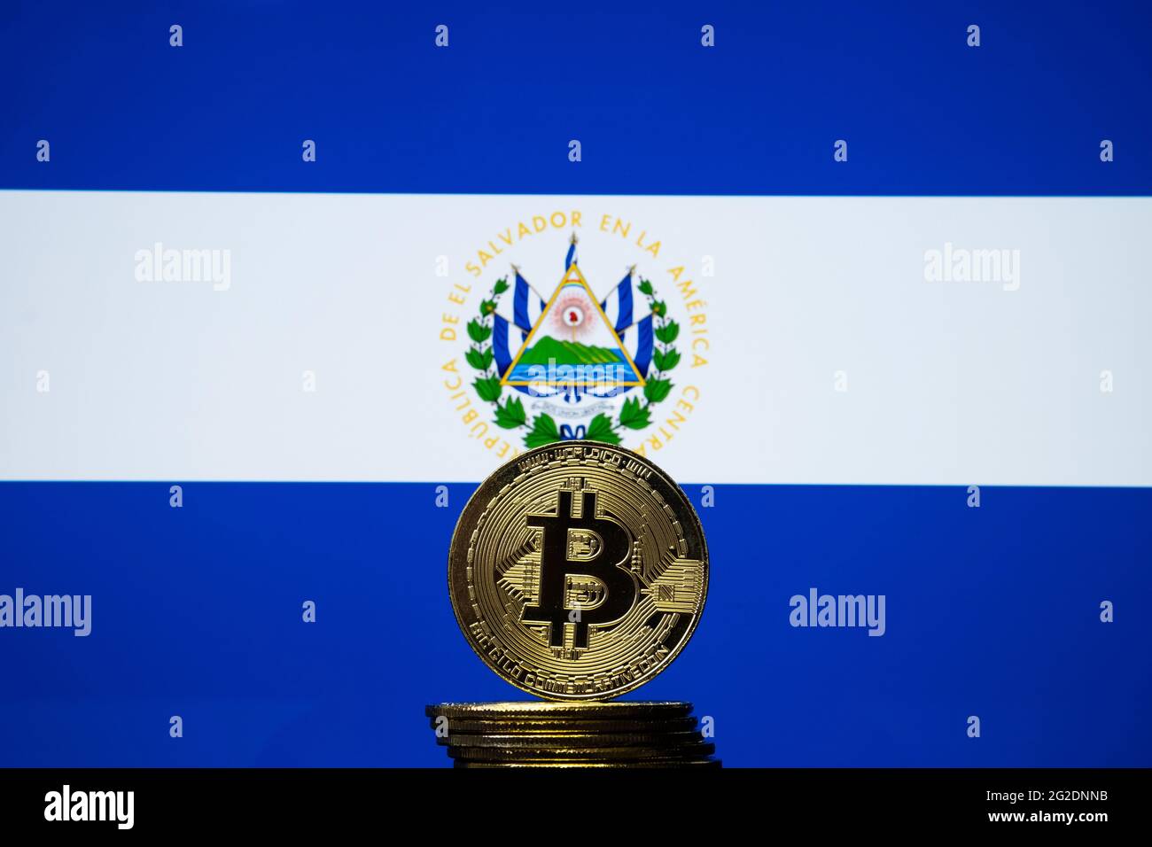 Bitcoin representation coin placed in front of blurred Salvador's national flag. El Salvador is the first country to adopt bitcoin as legal tender. Co Stock Photo