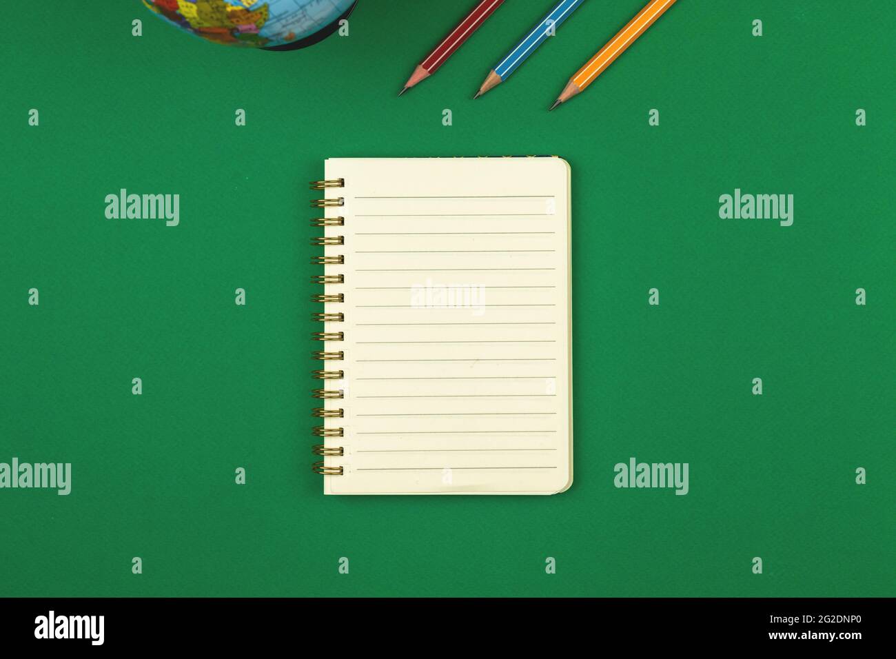 Green school table with blank lined notebook and pencils top view photo with copy space Stock Photo