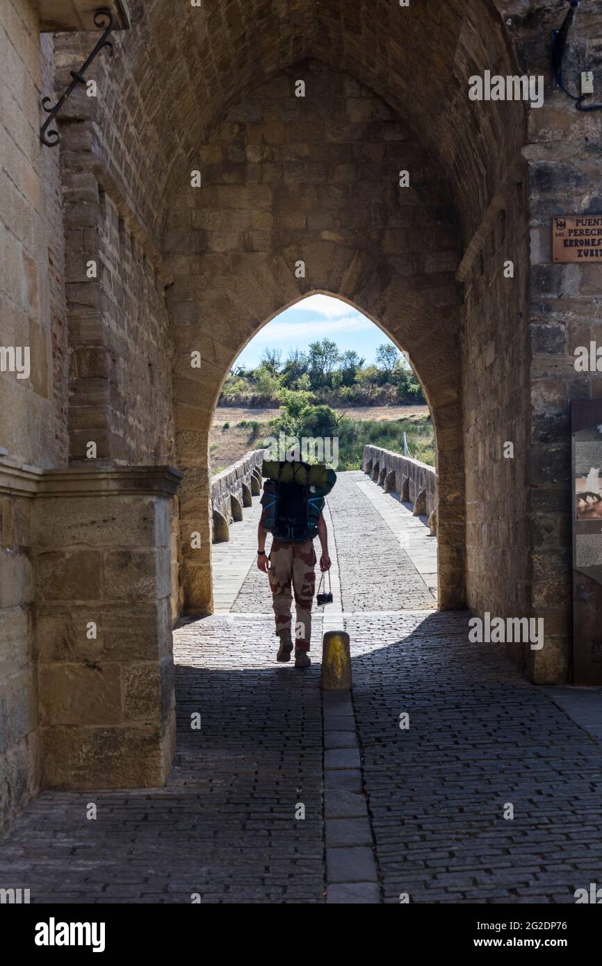 A pilgrim crosses Puente la Reina Bridge along the Camino de Santiago. Saint Jacques Way. Navarra. Spain Stock Photo