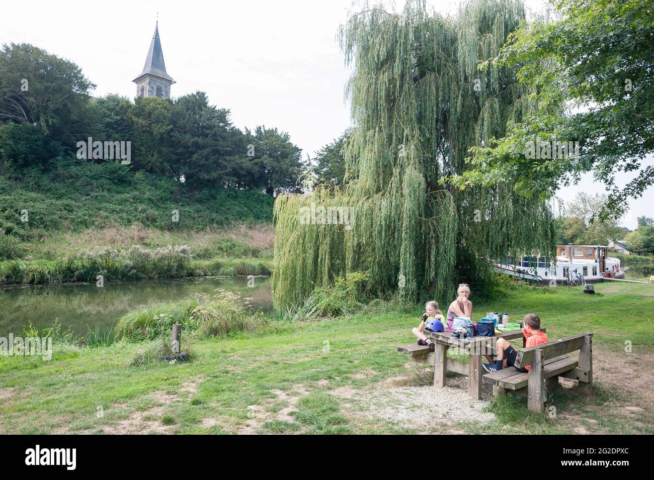 A family eating a packed lunch on a bench in France while out on a bike ride. Stock Photo