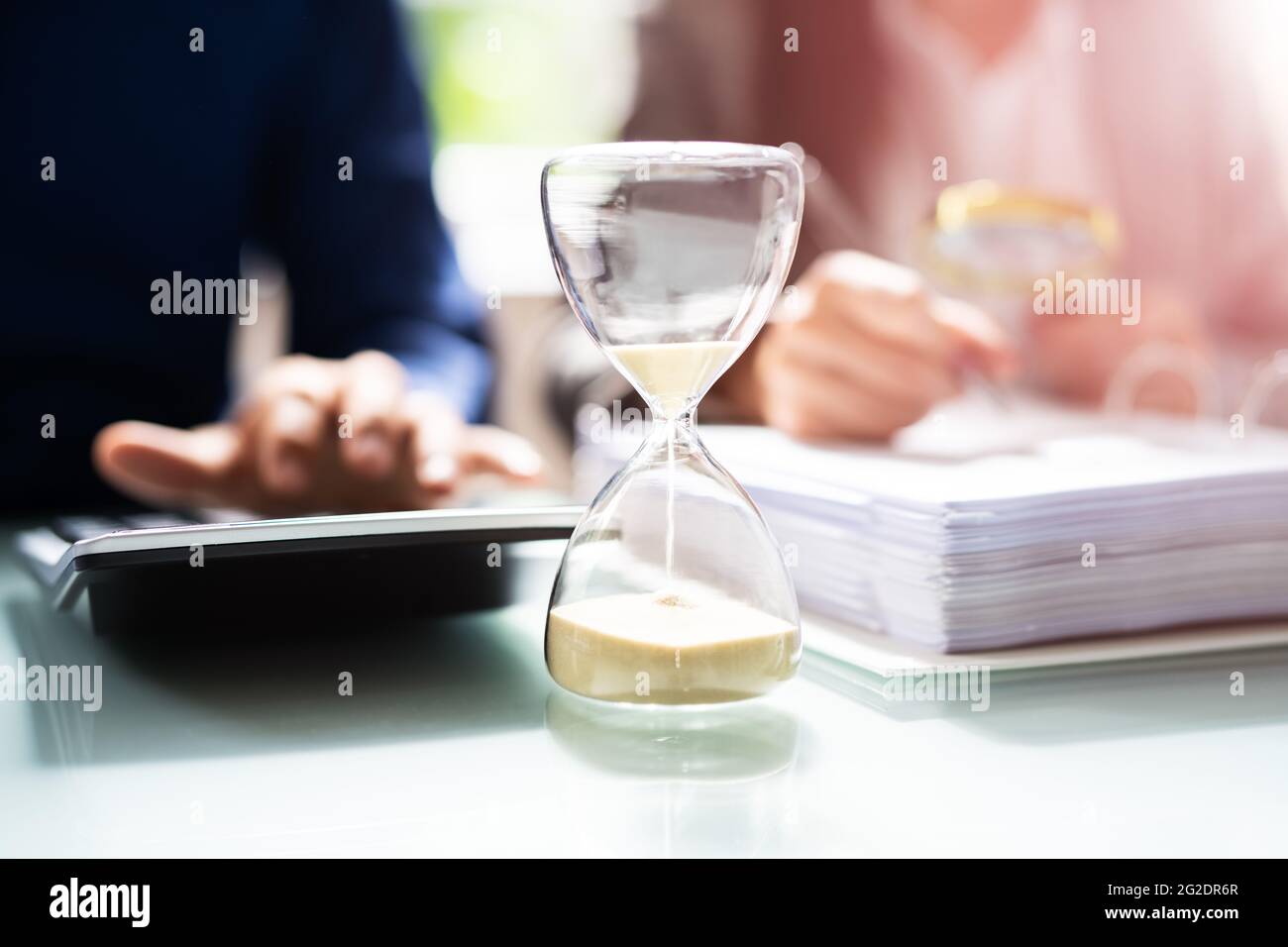 Hourglass And Time Crunch With Document In Office Stock Photo