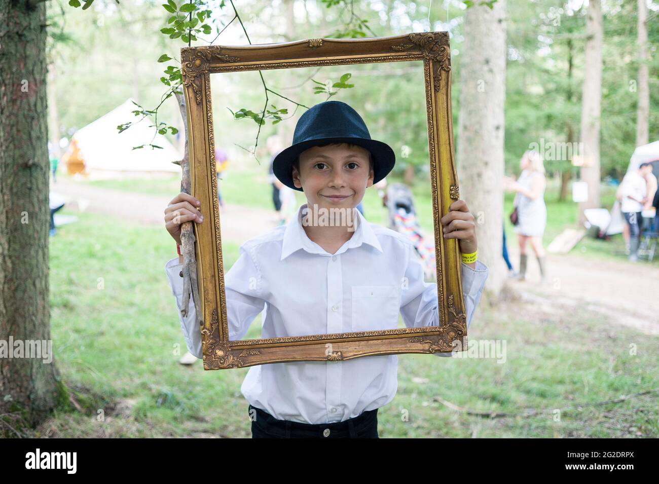 A young boy holds a picture frame at a festival in the forest Stock Photo