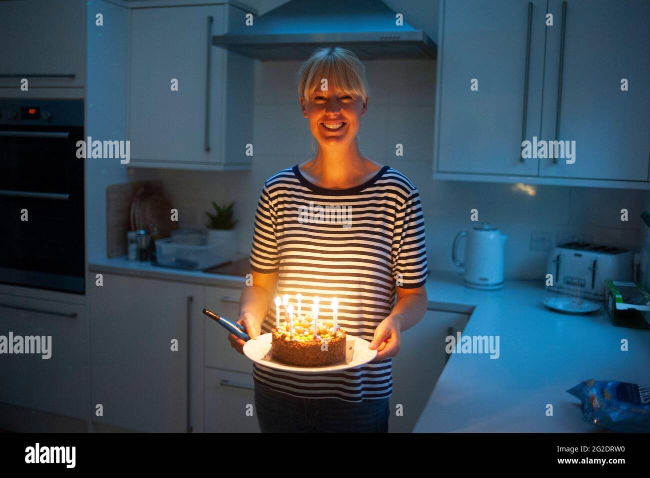A mother carries a birthday cake after lighting the candles in her