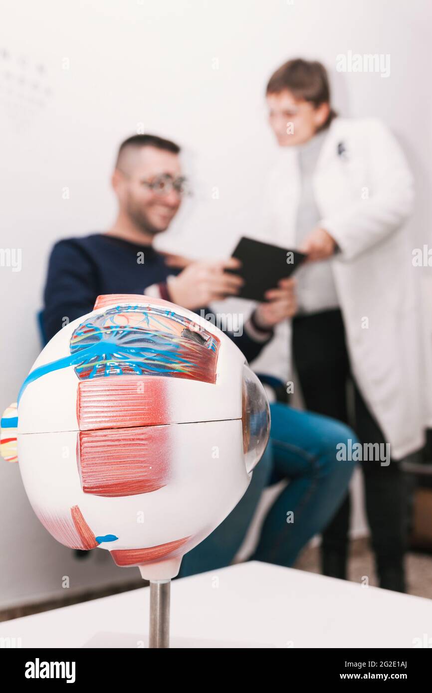 An optician patient follows an optometrist's instructions to read a reading chart during a vision graduation. They are out of focus in the background, Stock Photo