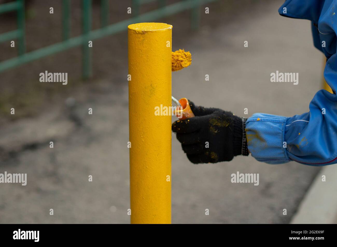 Painting a metal post with yellow paint. Parking bollard painting