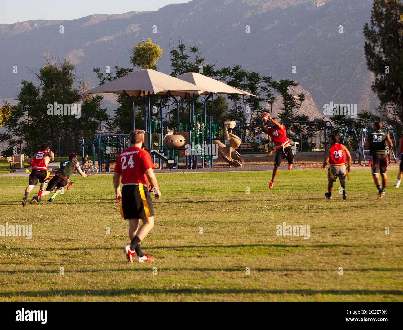Young men playing flag football at a public park. Stock Photo