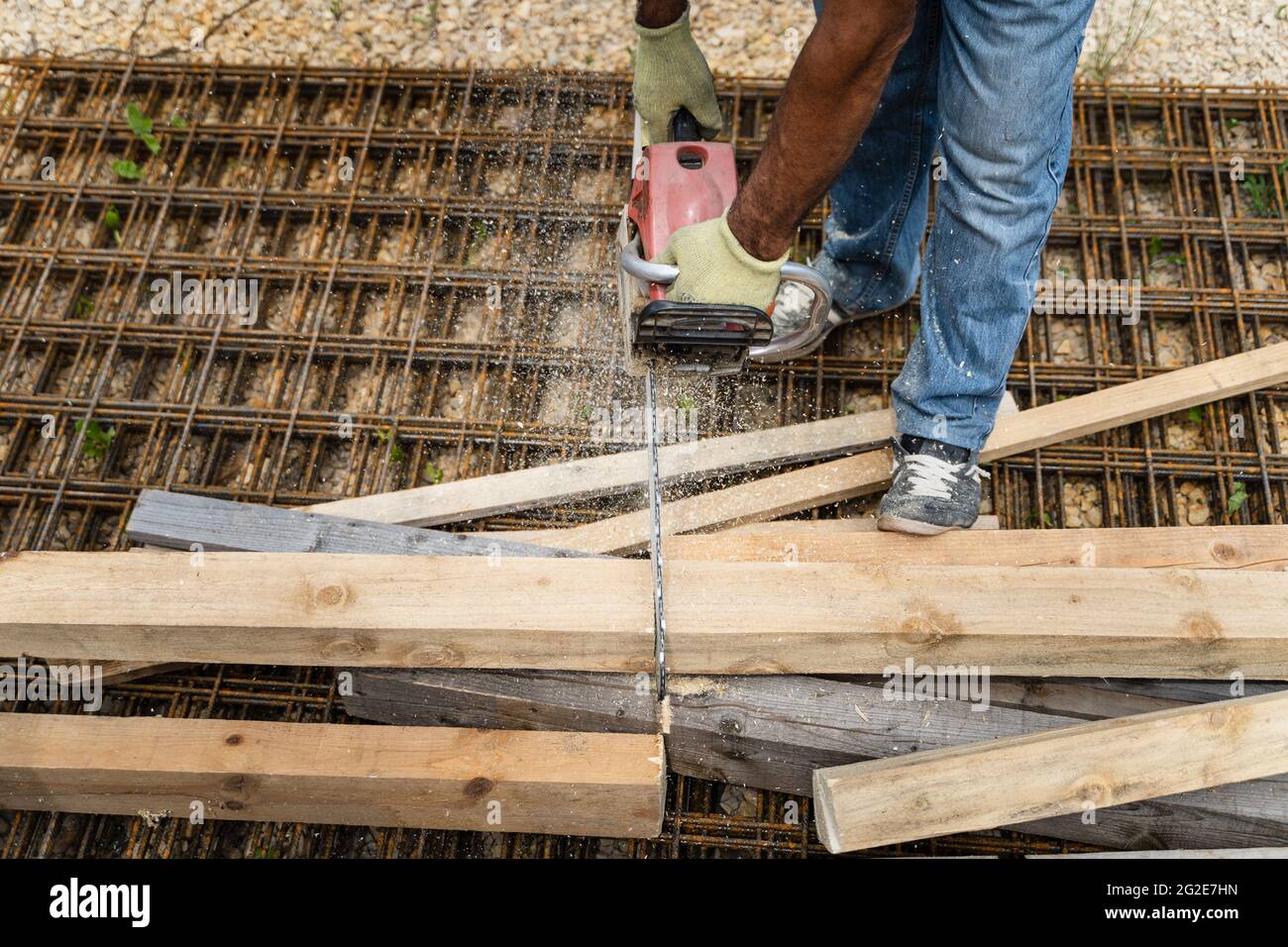 Close up on hands of unknown man holding chainsaw at warehouse or construction site sawing and cutting lumber wood Stock Photo