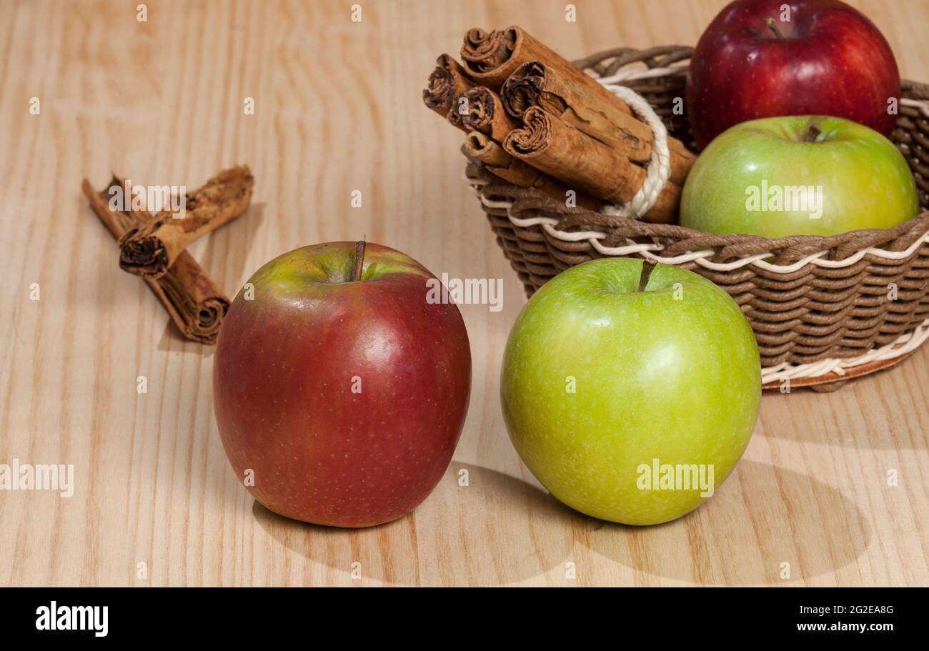Red and green apple with a cinnamon stick; photo on wooden background. Stock Photo