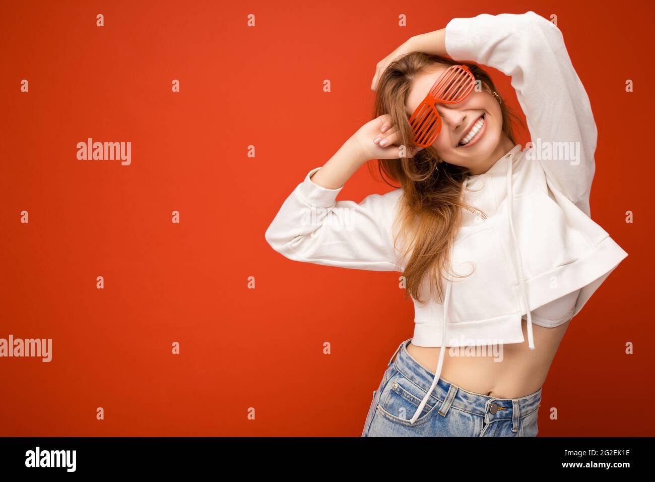 Photo shot of beautiful positive young blonde woman wearing casual clothes and stylish optical glasses isolated over colorful background wall looking Stock Photo