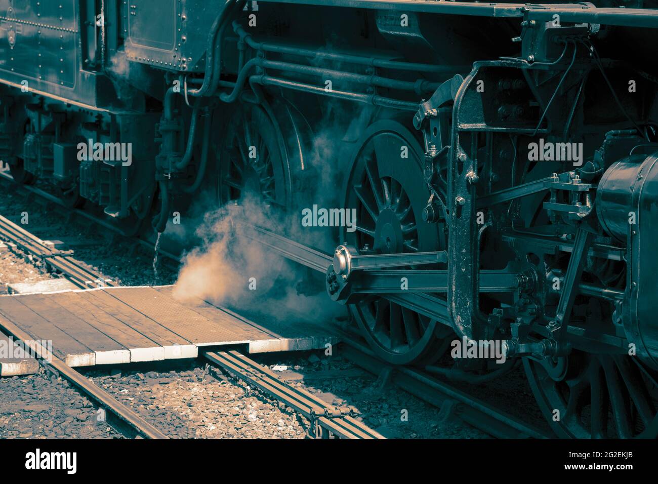 Steam train engine wheels closeup with steam coming out