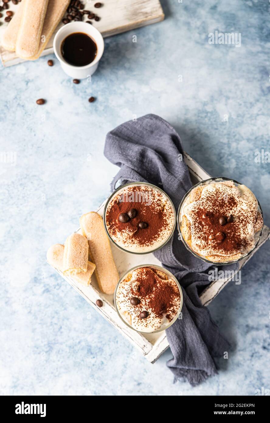 Traditional Italian dessert tiramisu in glass, light stone background
