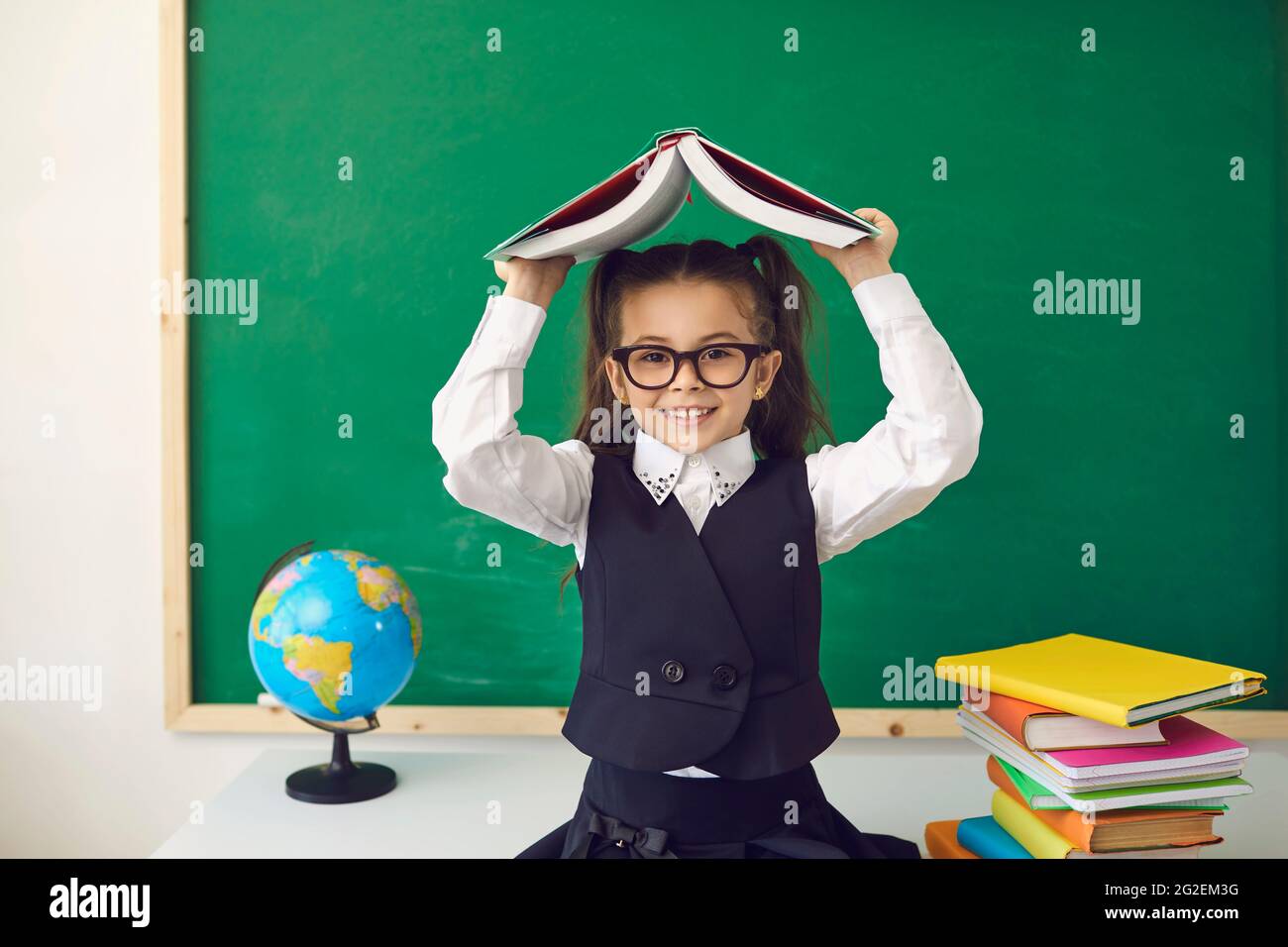 Back to school concept. Little girl with a book over her head smiling ...