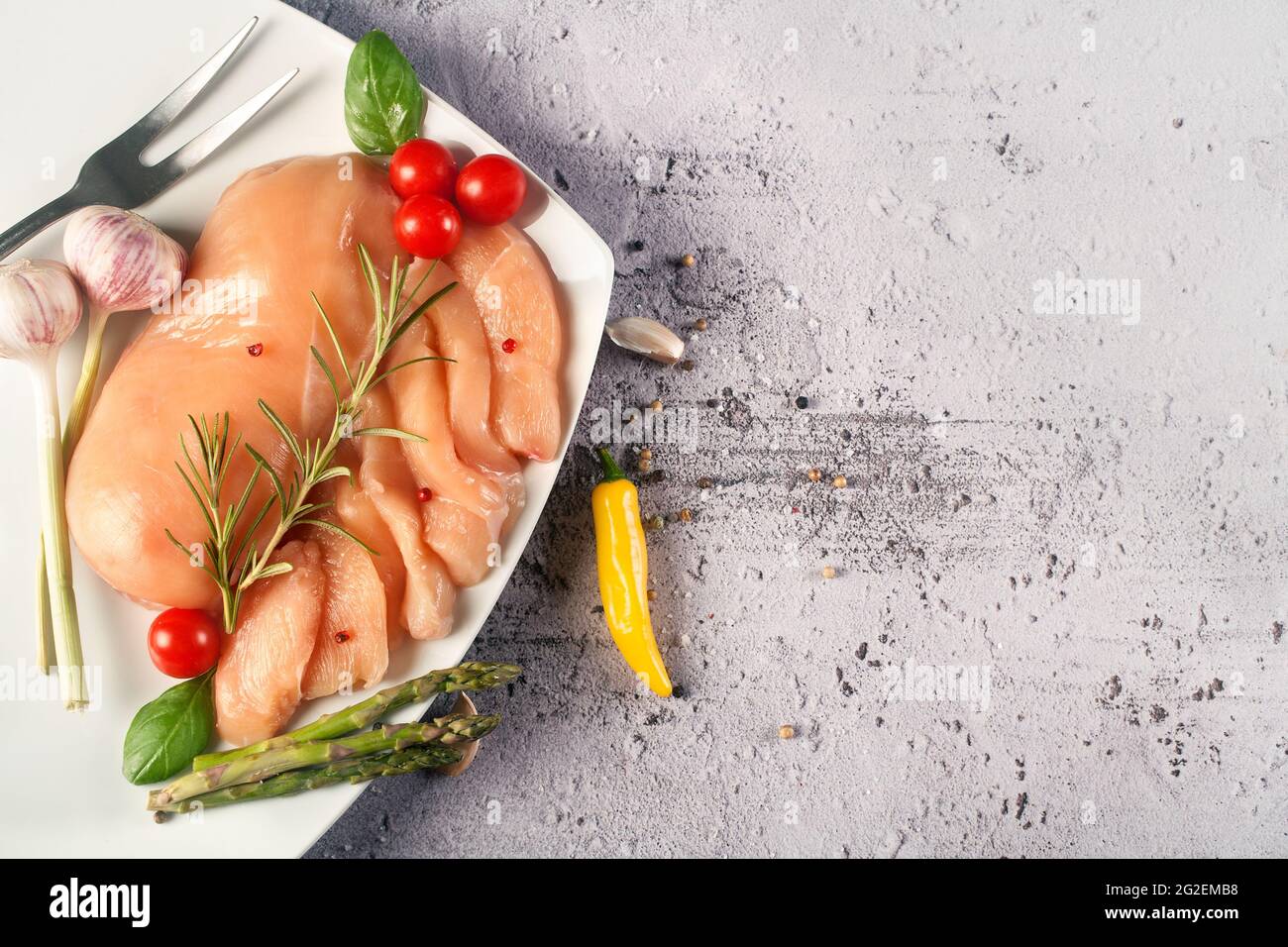 Fresh chicken breasts on a wooden board with organic vegetables, the concept of a healthy diet Stock Photo