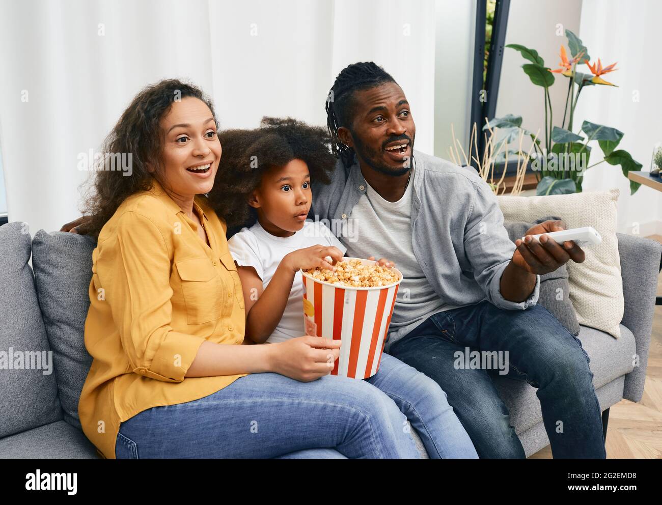 Mixed race family of three watching TV or home cinema theatre with