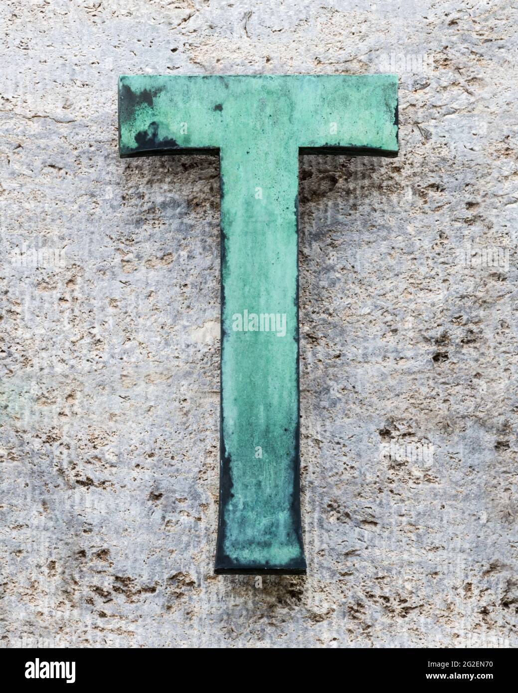 Metal letter T on a house wall covered with verdigris on a natural stone wall Stock Photo