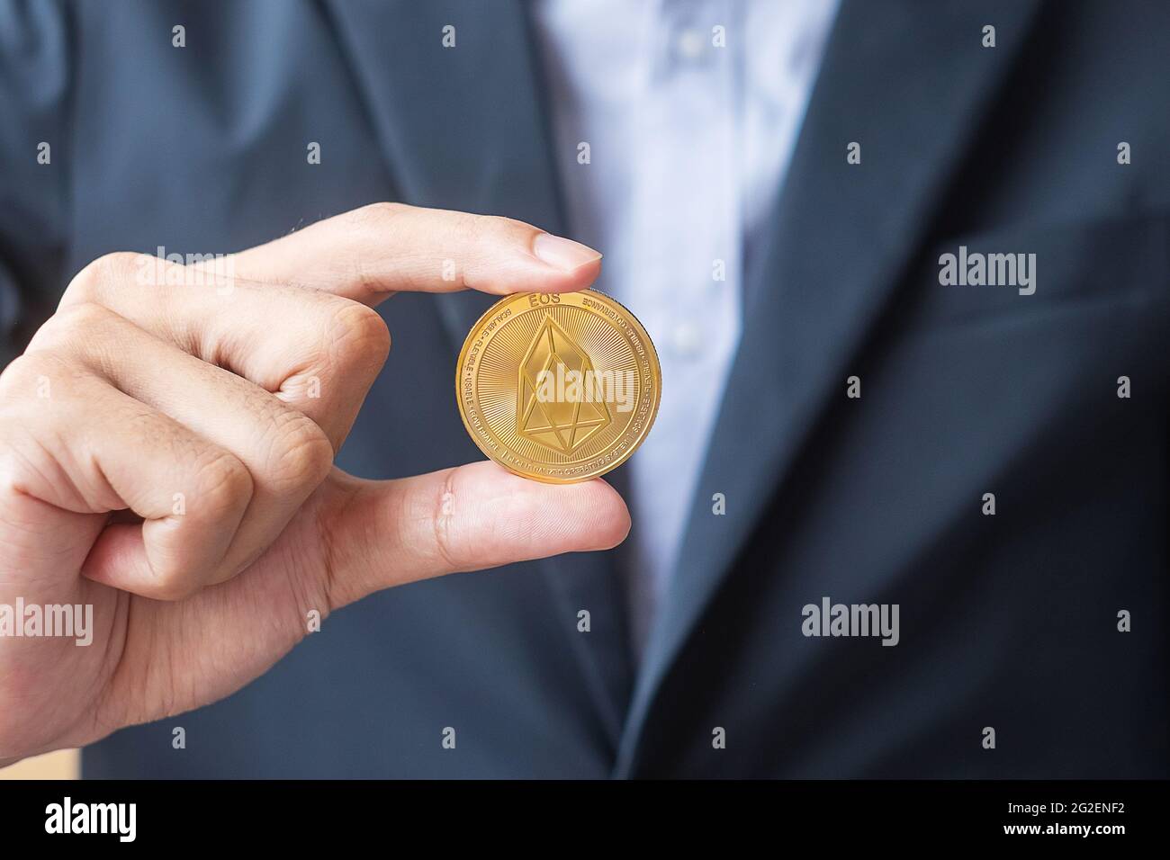 man hand holding gold EOS coin cryptocurrency, Crypto is Digital Money within the blockchain network, is exchanged using technology and online exchang Stock Photo