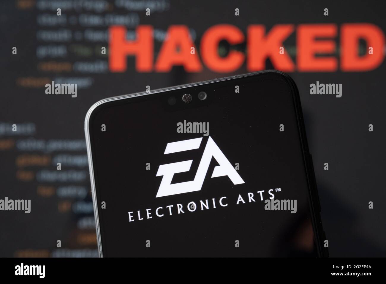 EA Electronic arts logo seen on a silhouette of the smartphone and simple source code on with word HACKED on blurred background. Concept. REAL PHOTO, Stock Photo
