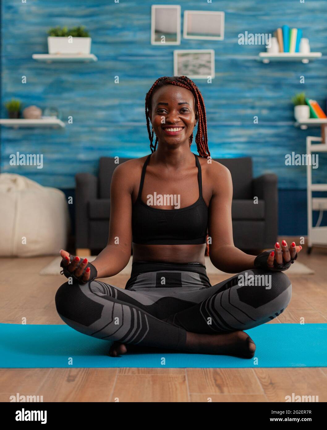 Portrait of black woman smiling practicing yoga at home sitting in ...