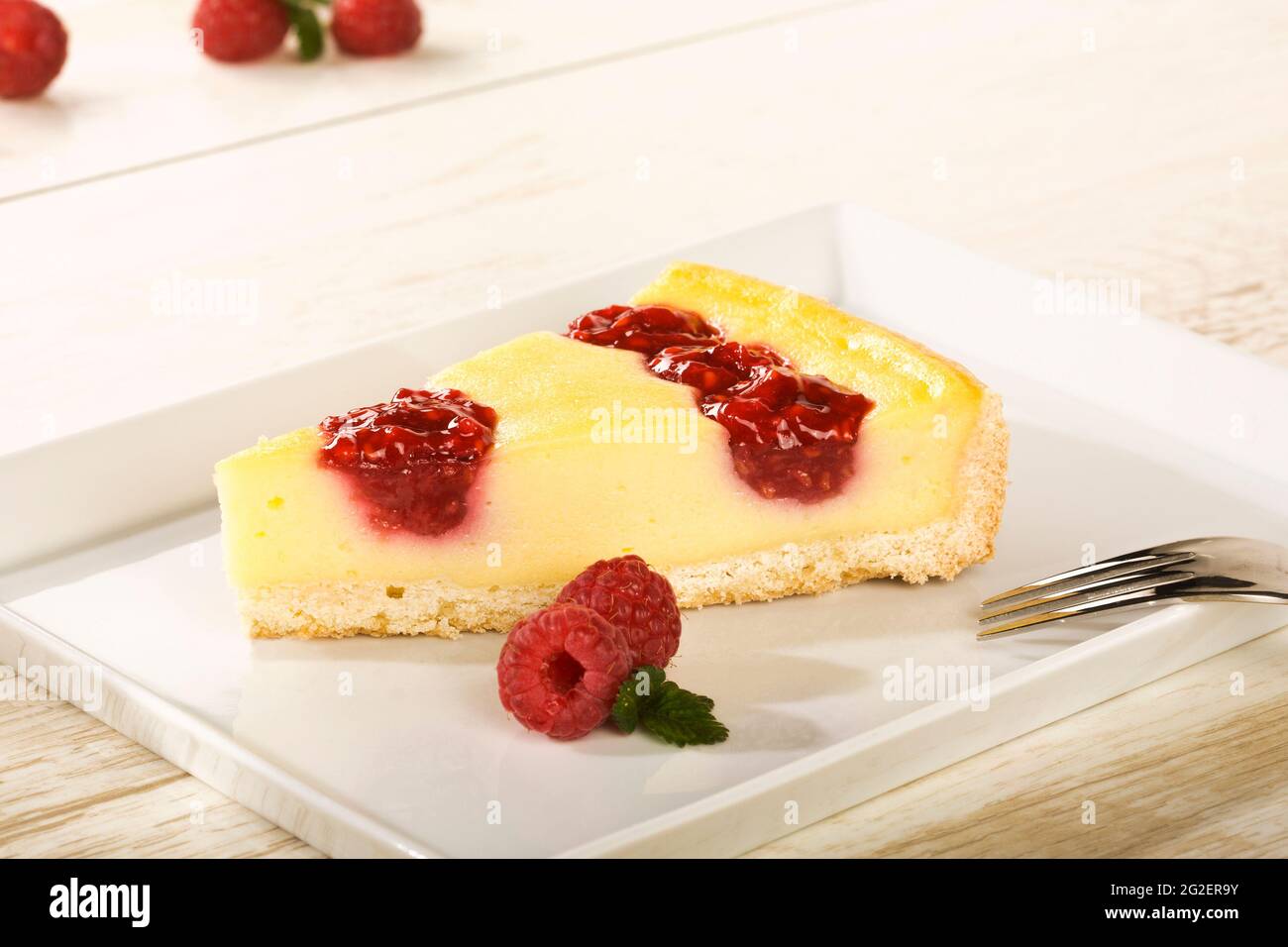 piece of raspberry cheesecake on square white plate Stock Photo