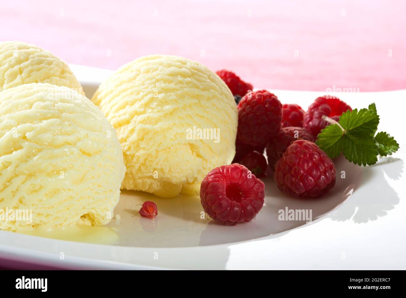 three scoops of vanilla icecream garnished with raspberries Stock Photo