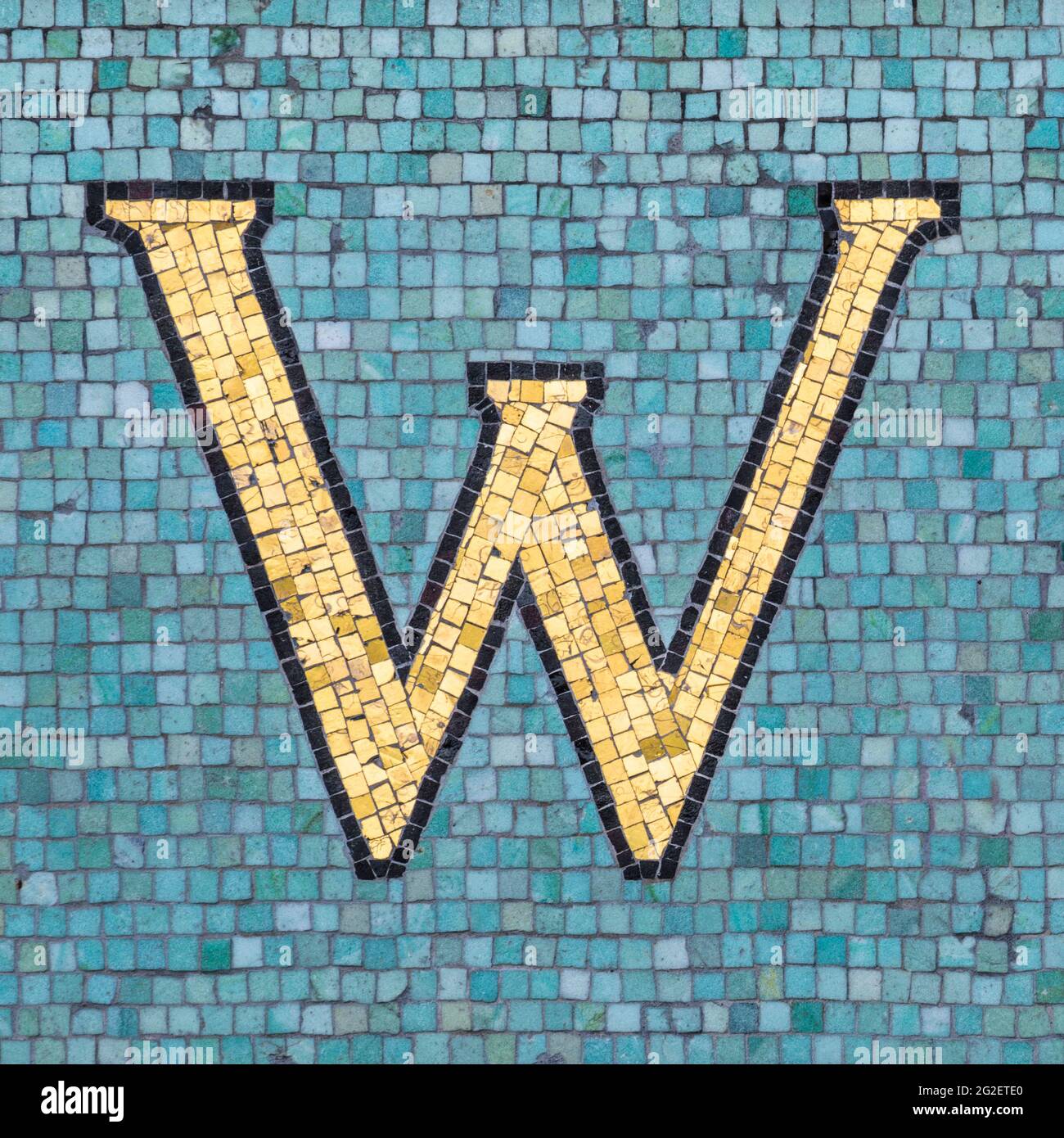 Golden mosaic letter W with black outline in turquoise blue mosaic ...