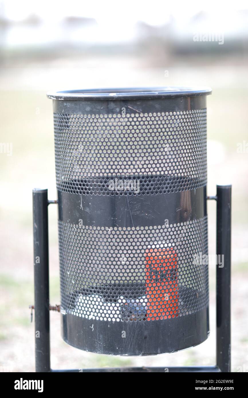 empty trash can in the middle of a park on the street Stock Photo