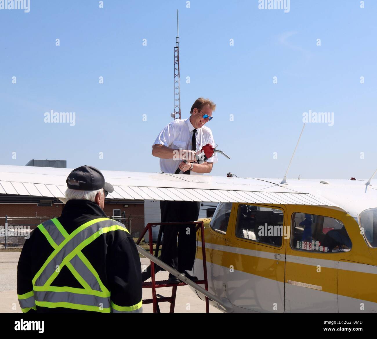 WIARTON, CANADA - Apr 04, 2021: Hanover, Ontario  Canada- April 4, 2021: A male flight instructor fueling up a yellow and white Cessna 172 as an airpo Stock Photo