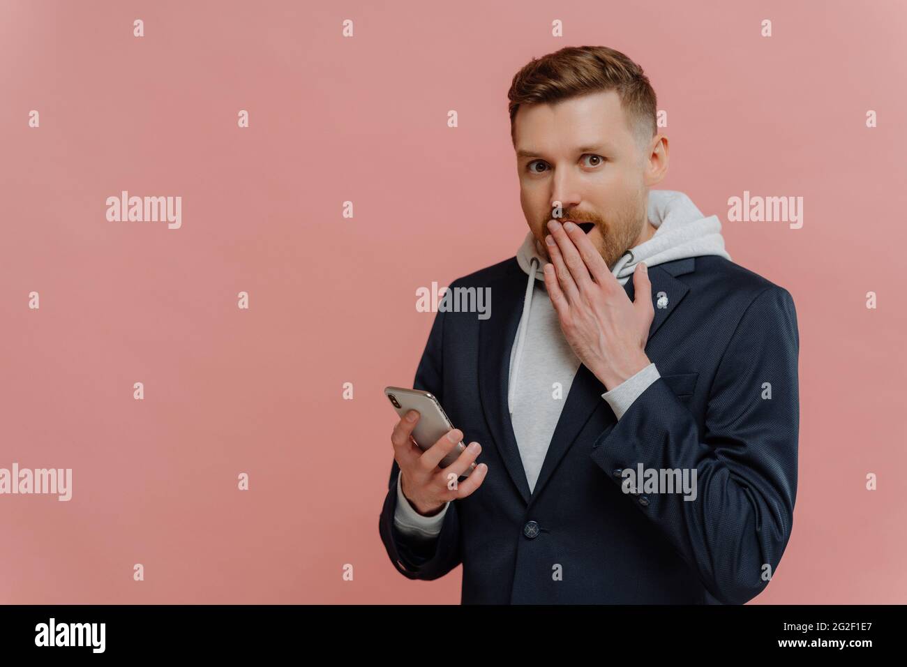 Young man receiving shocking message on smartphone Stock Photo