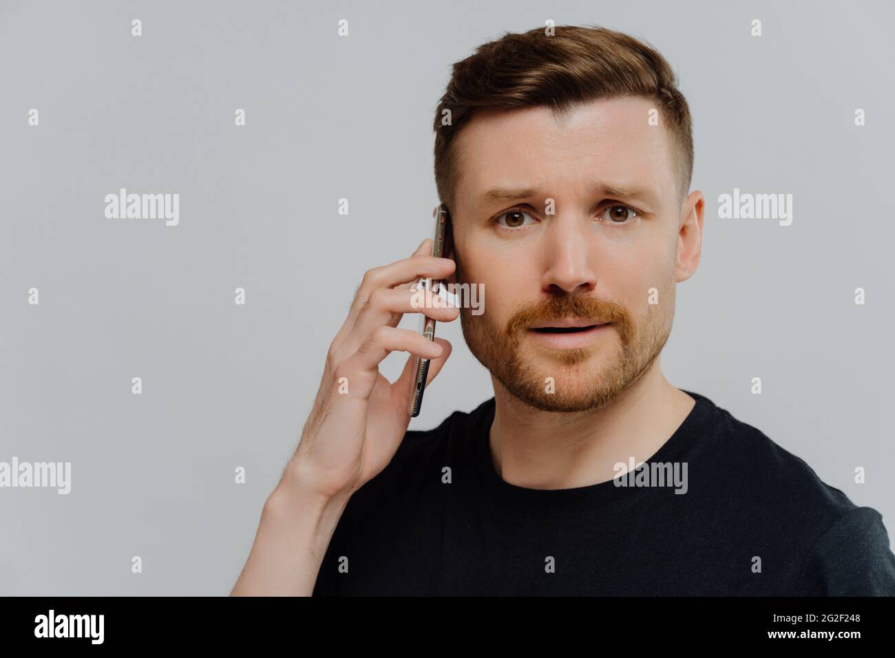 Worried man having unpleasant conversation on mobile phone and feeling unhappy Stock Photo