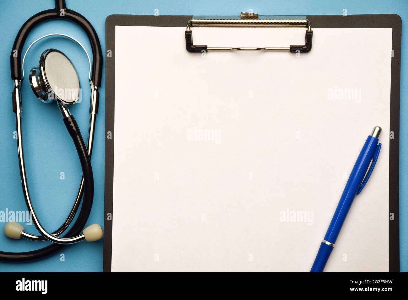 Stethoscope and clipboard on a blue background with pen. There is a ...