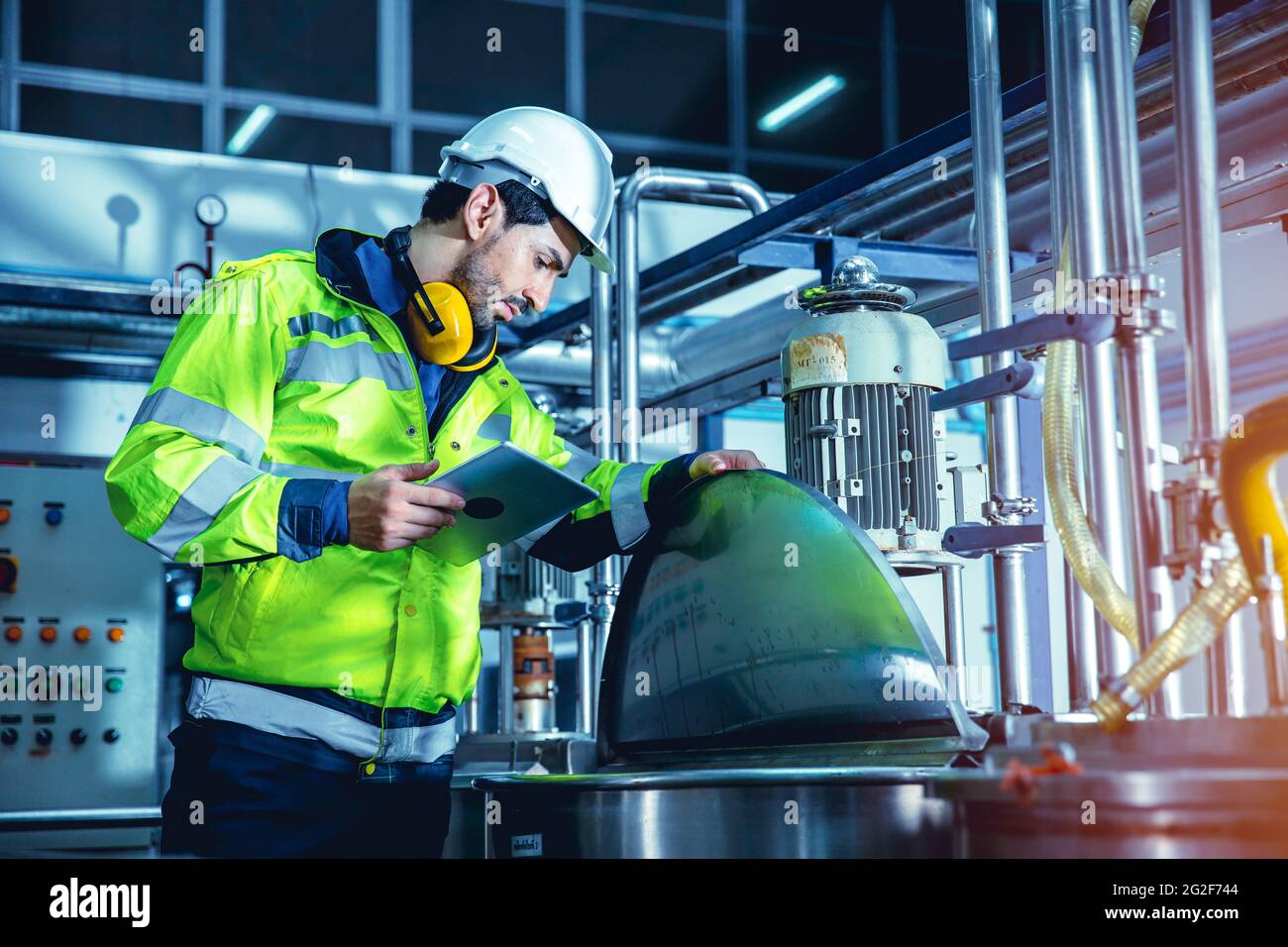 Factory worker engineer working in factory using tablet computer to check maintenance boiler water pipe in factory. Stock Photo