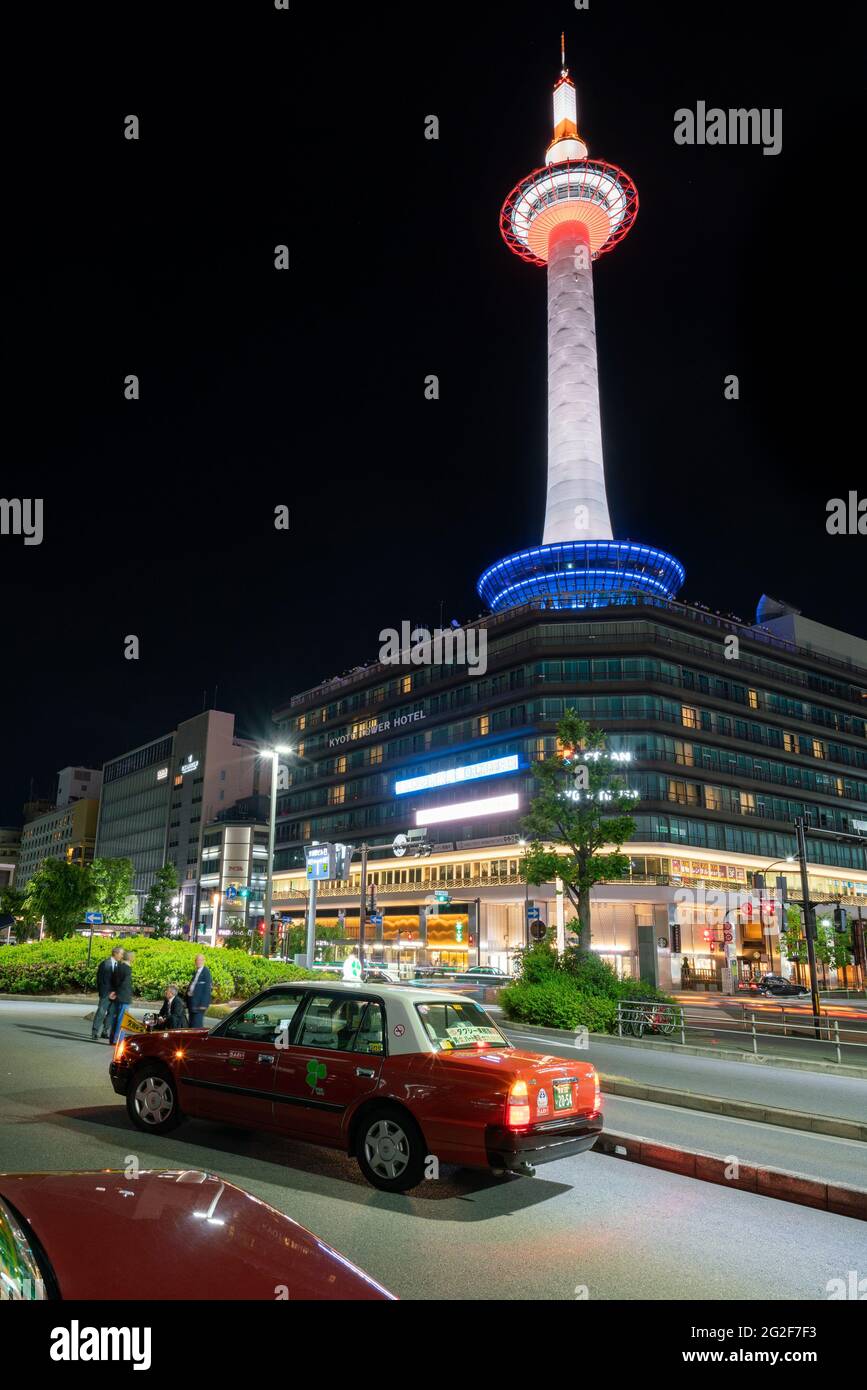 Tokyo, Japan - 15.05.2019: Vertical low angle shot of Kyoto Tower illuminated in different colors in the night from the street below with traditional Stock Photo