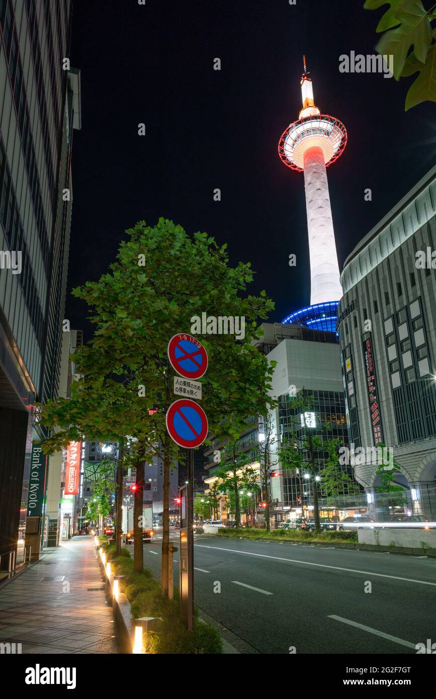 Tokyo, Japan - 15.05.2019: Vertical low angle shot of Kyoto Tower illuminated in different colors in the night from the street below Stock Photo