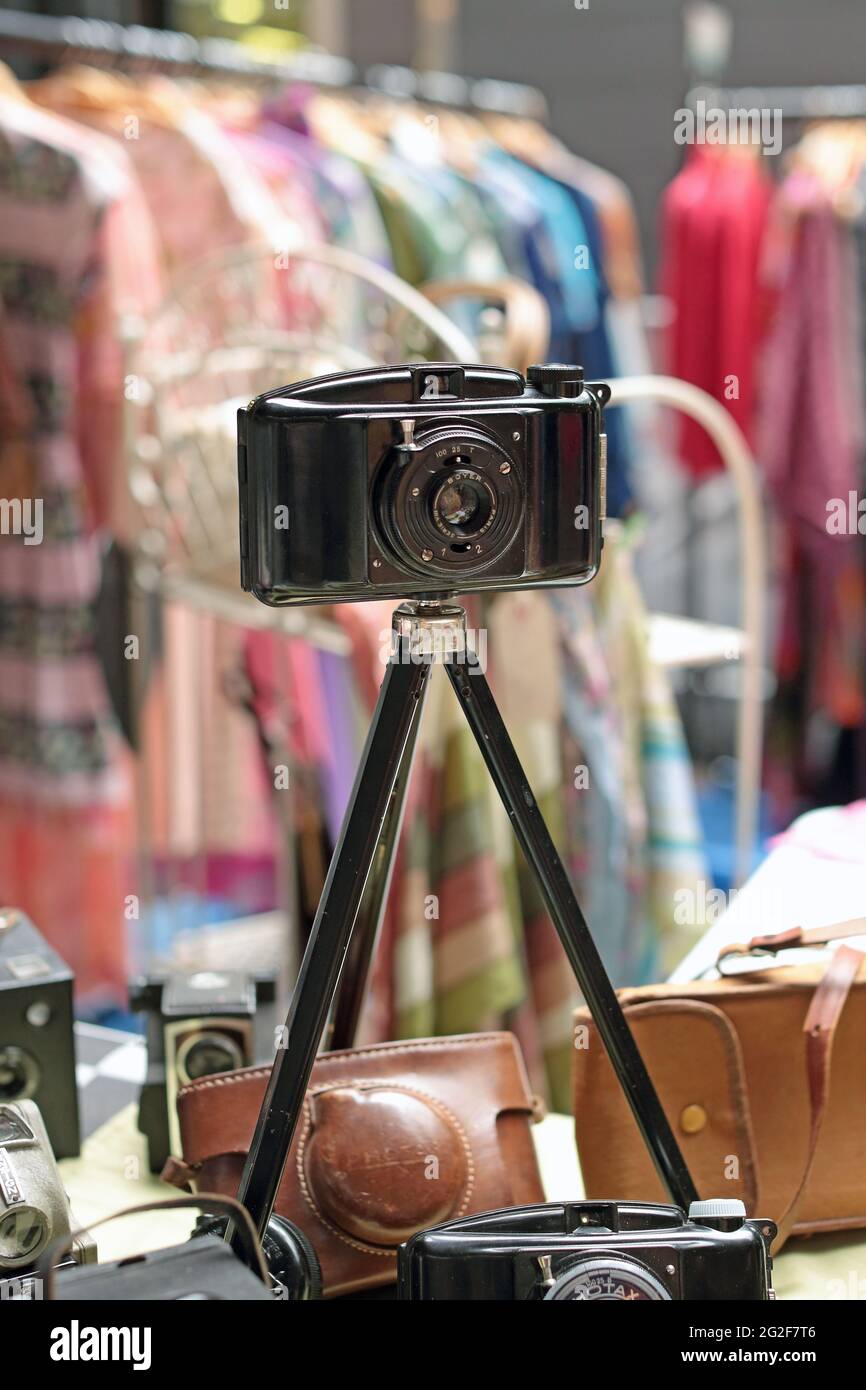 Old Vintage camera on tripod on sale in a stall at the Classic Car Boot Sale at Granary Square in King's Cross London. Stock Photo