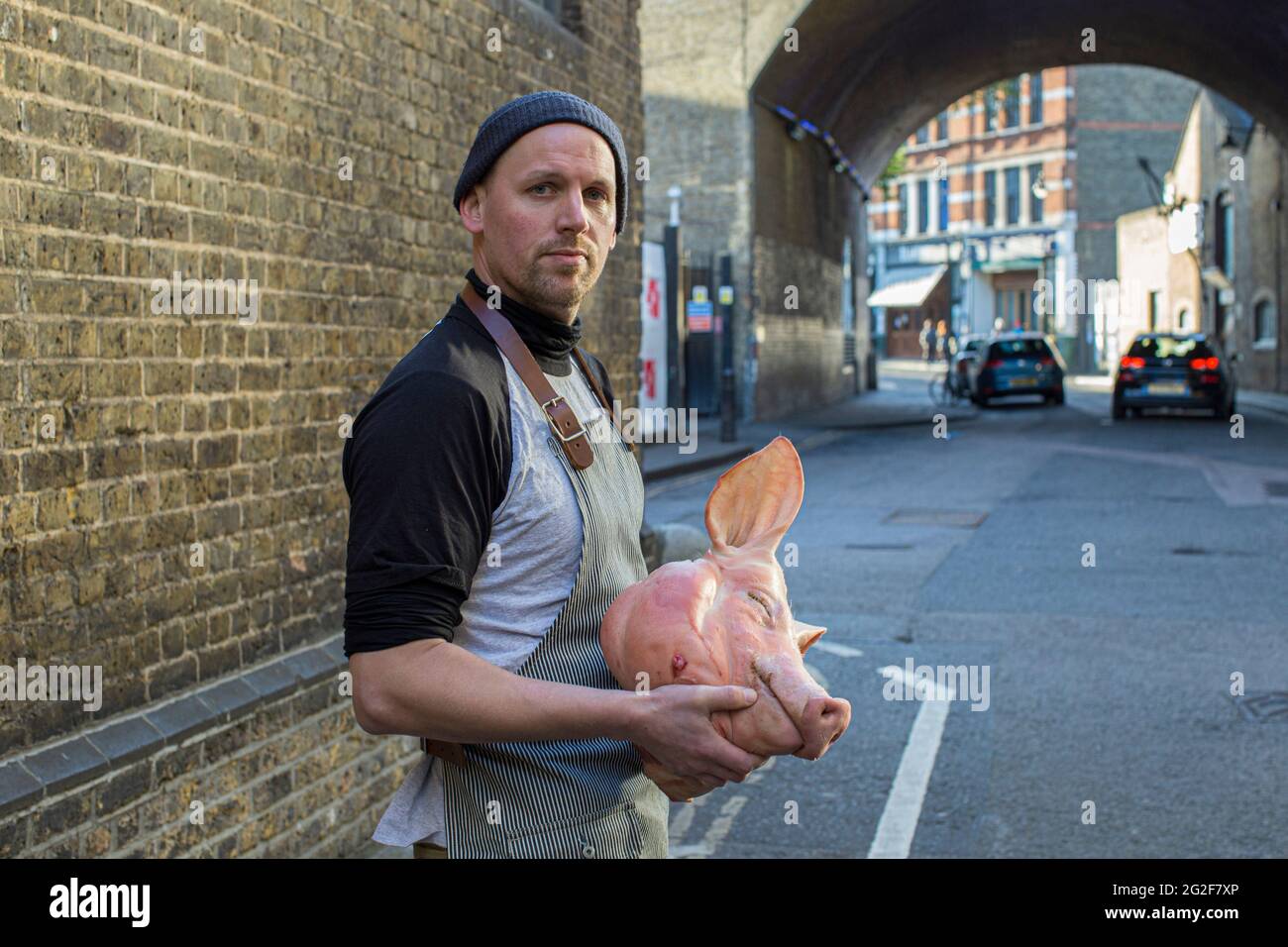 GREAT BRITAIN / England / Butcher holding a pigs head at borough market in London . Stock Photo