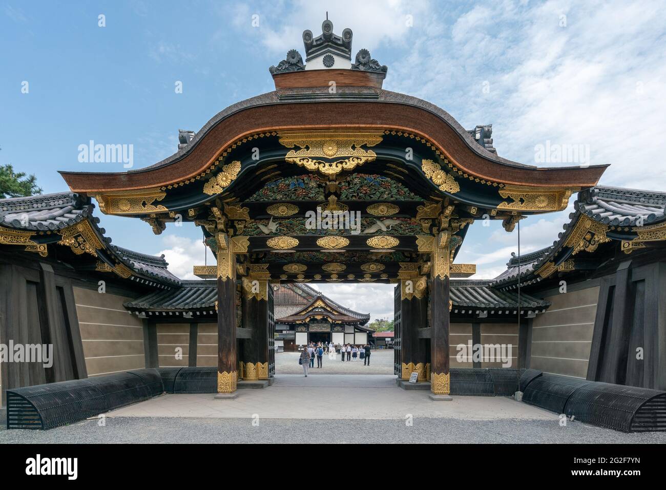 Kyoto, Japan - 05.30.2019: Look through the richly decorated gate of Nijo castle, Kyoto, Japan. People gathering in the courtyard of famous ancient Bu Stock Photo