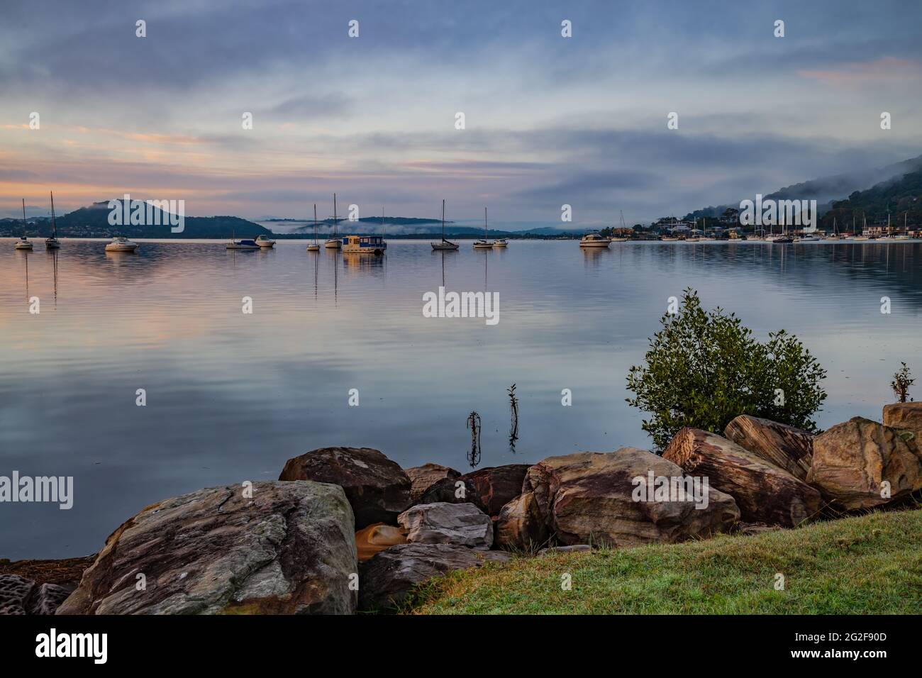 A soft pretty sunrise with boats and fog at Koolewong Waterfront on the Central Coast, NSW, Australia. Stock Photo