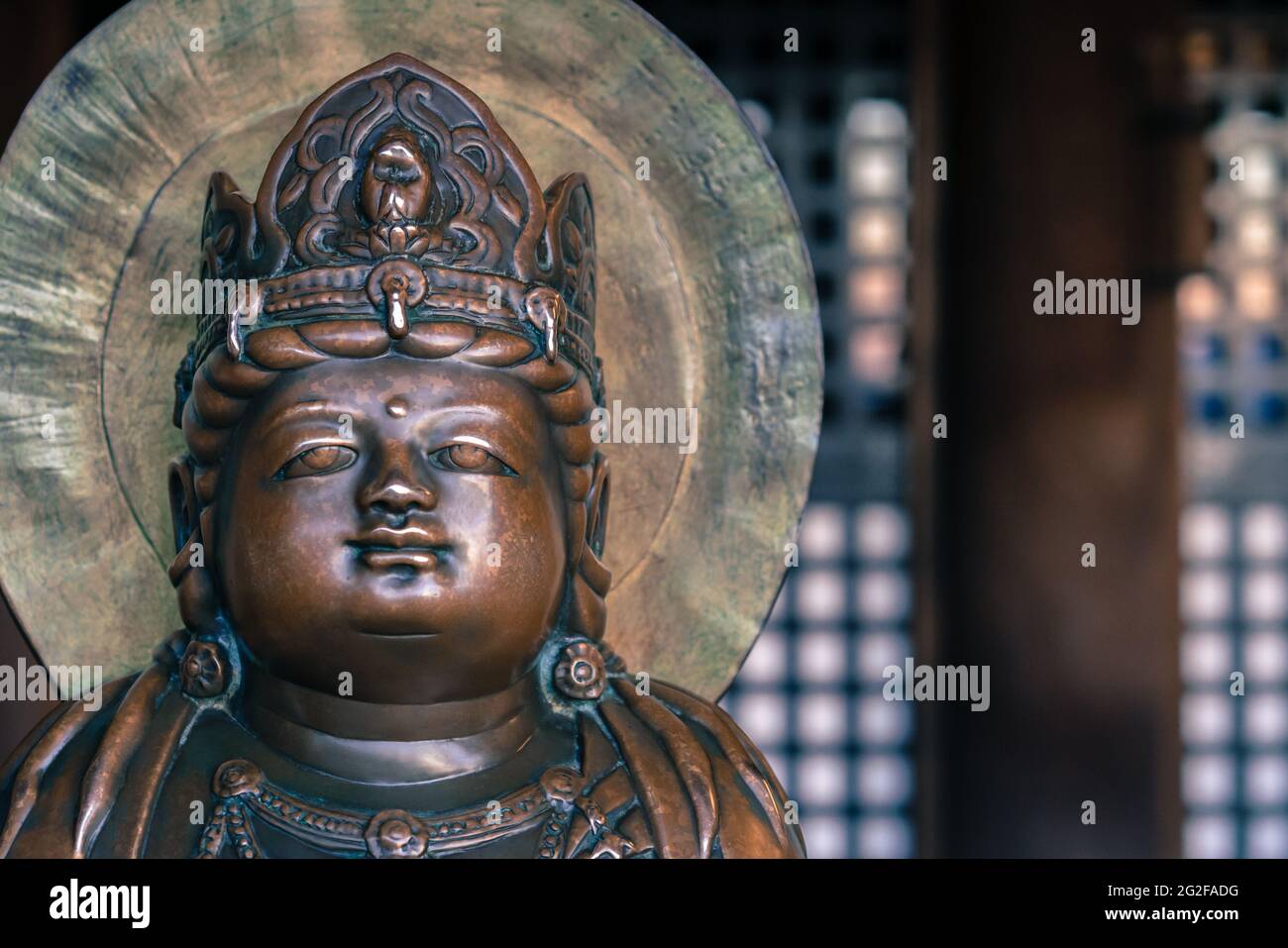 Small bronze Buddha statue with crown on his head in an old Buddhist temple of Kiyomizu Dera in Kyoto, Japan. Arts and symbols of Buddhism in the far Stock Photo