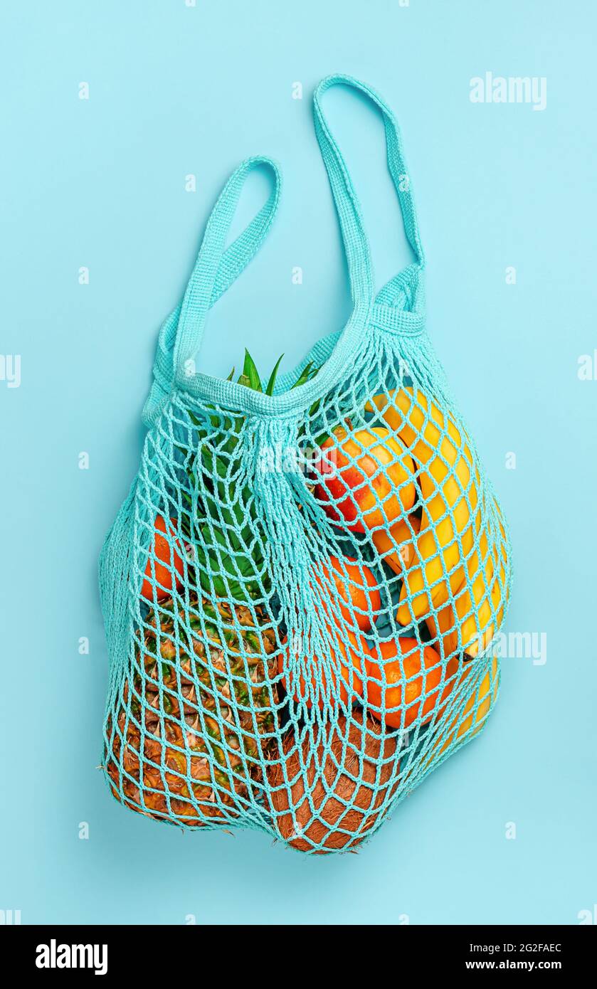 Organic fruits in reusable net bag on blue background. Top view. Stock Photo
