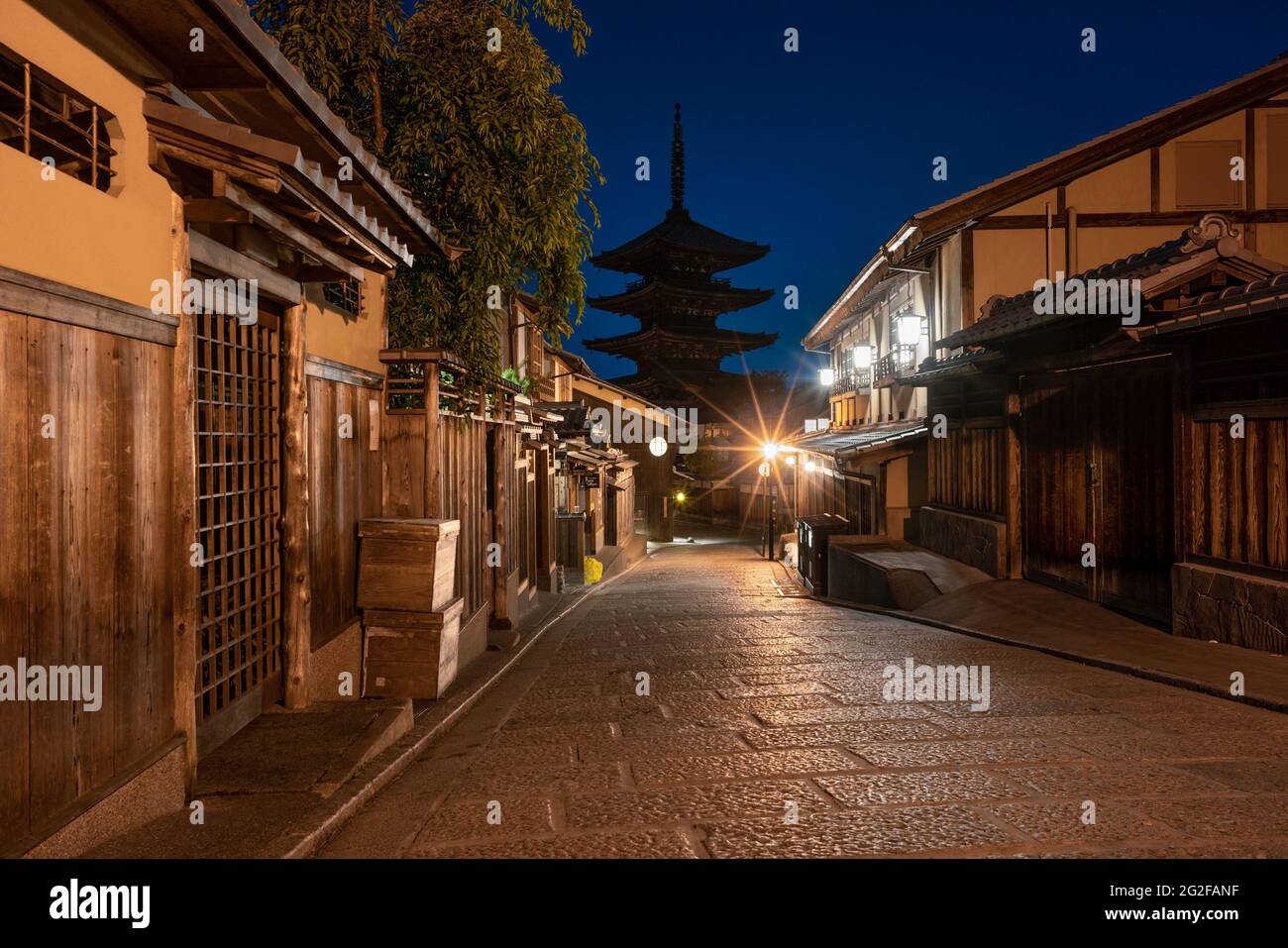 Ancient Buddhist temple of Hokan-ji in old town of Kyoto in the early night, viewed from narrow street below. Blue glowing sky contrasts with traditio Stock Photo