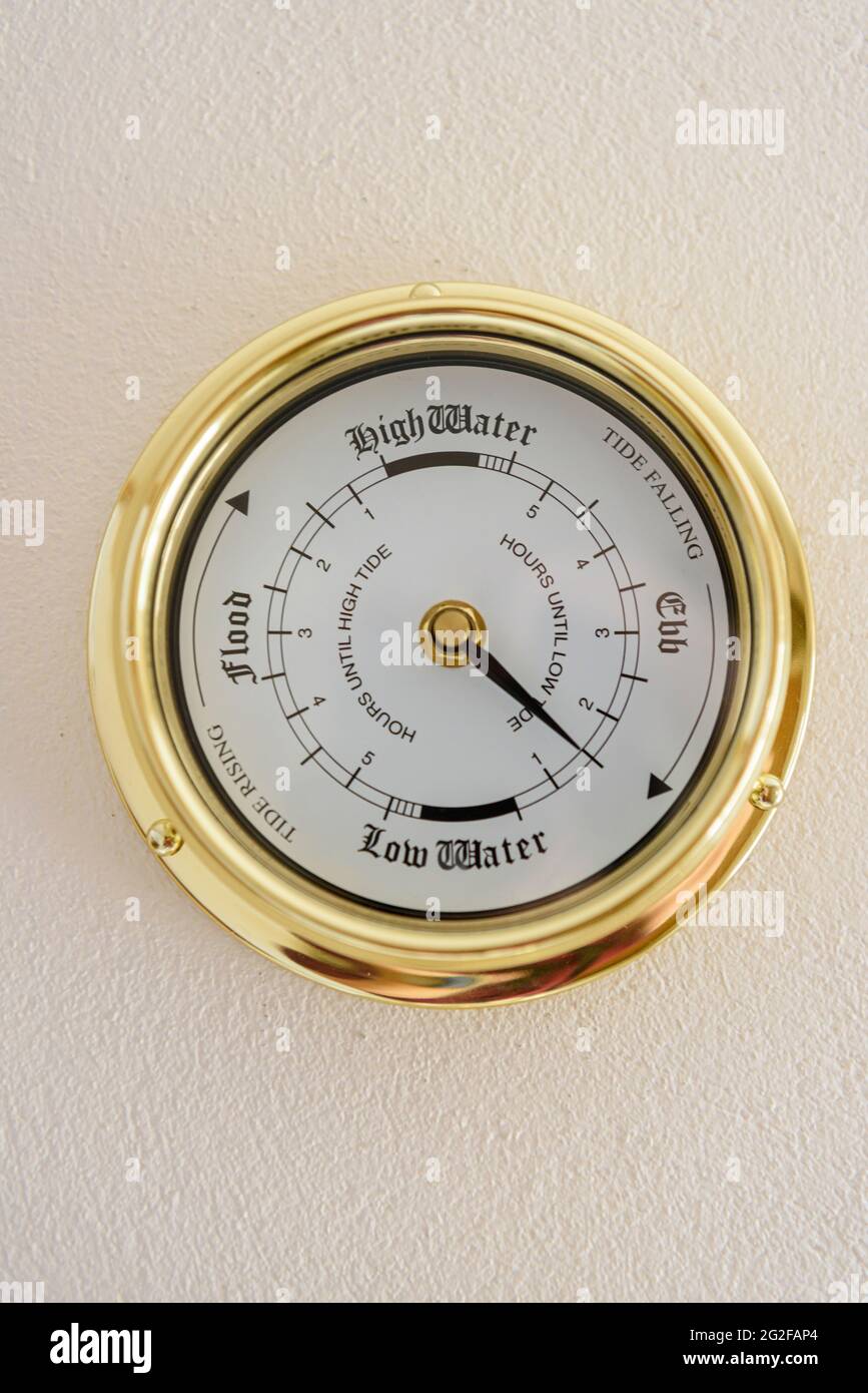 Brass tidal clock on a wall, with a single hand which rotates once ever 12 hours 25 minutes (half the lunar day). Stock Photo
