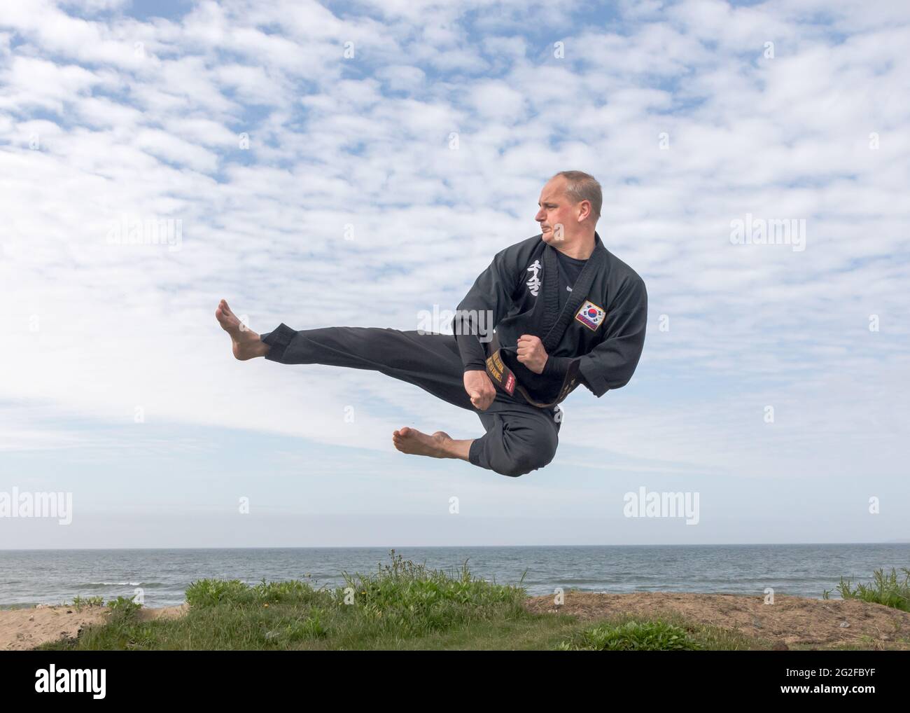 Garrylucas, Cork, Ireland. 11th June, 2021. Matthew Boniwell from Ballinspittle, a 5th degree black belt master in the Korean martial art of Kuk Sool Won, does some warm up exercises prior to conducting a keep fit class on the seafront at Garrylucas, Co. Cork, Ireland.   - Credit; David Creedon / Alamy Live News Stock Photo
