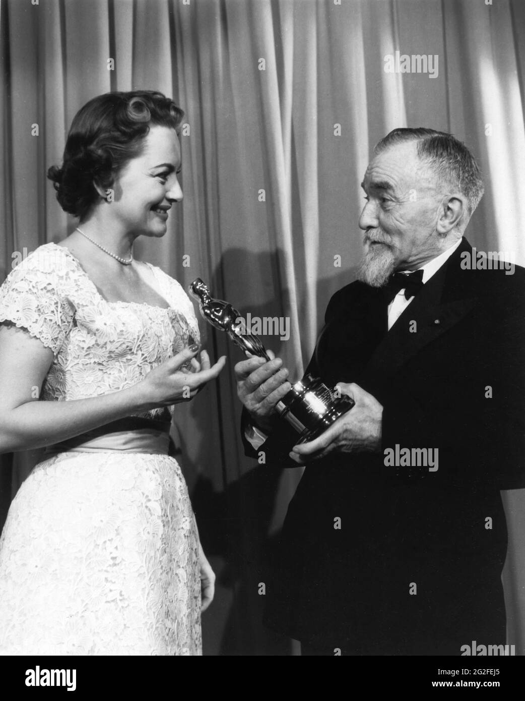 OLIVIA de HAVILLAND presents French Professor HENRI CHRETIEN with his Oscar / Academy Award of Merit for his invention of the Anamorphic Lens used in the CinemaScope Process circa 25th March 1954 at the Cannes Film Festival which began at the same time as the 1954 26th Academy Awards Ceremony in Los Angeles publicity for Twentieth Century Fox Stock Photo