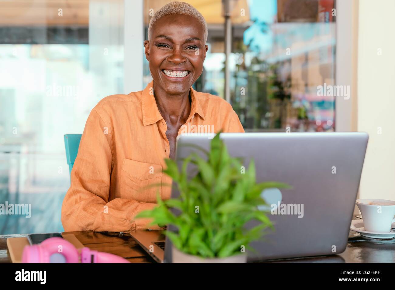 Happy African woman working online using laptop in bar restaurant - Digital nomad and freelance lifestyle concept Stock Photo